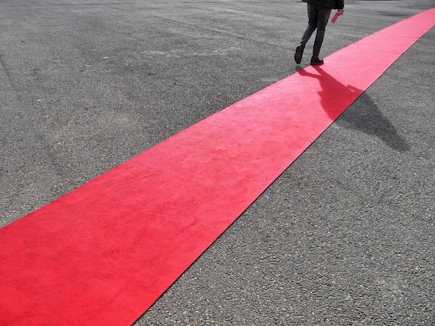 Foto primo piano di una persona che cammina su un tappeto rosso