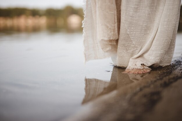 Photo closeup shot of a person wearing a biblical robe walking on the shoreline