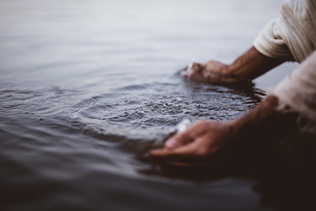 Крупный план человека в библейской одежде, моющего руки в воде