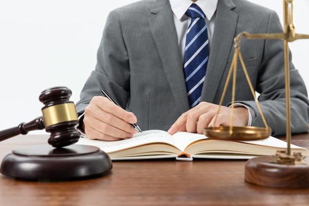 Closeup shot of a person writing in a book with a gavel on the table