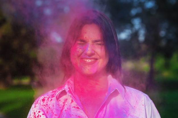 Closeup shot of positive caucasian woman with closed eyes celebrating Holi Festival