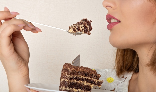 Foto colpo del primo piano di una bella donna con il trucco naturale che si gode una torta al cioccolato dolce. spazio per il testo