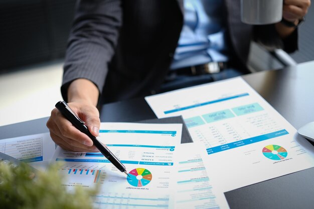 Closeup shot of professional businessman analyzing sales statistics document using laptop at working desk