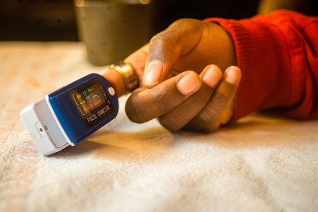 A closeup shot of a pulse oximeter on a black womans finger to measure pulse rate and oxygen levels