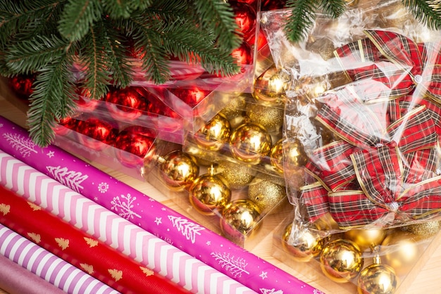 Closeup shot of red and golden Christmas tree baubles bows wrapping paper
