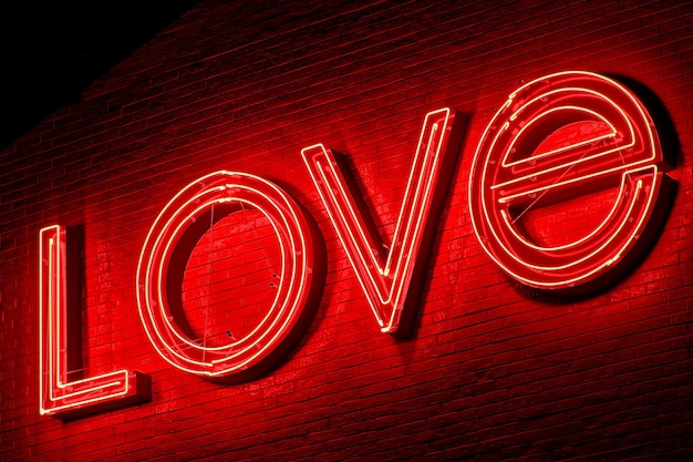 Closeup shot of a red neon sign LOVE on the brick wall at night the concept of love and romance