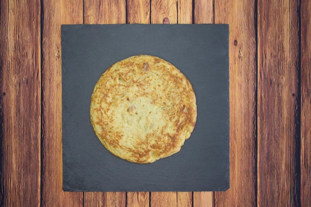 Foto una ripresa ravvicinata di un'omelette rotonda su un tavolo di legno