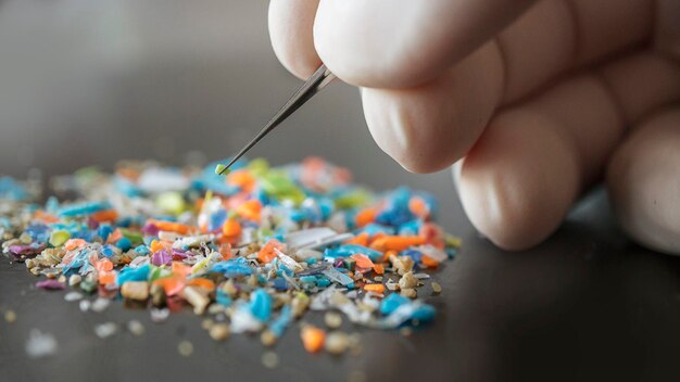 Closeup shot of a scientist with medical gloves inspecting micro plastics collected from the beach