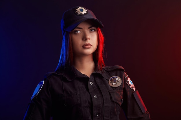 Closeup shot of serious female police officer posing for the camera against a black background with ...