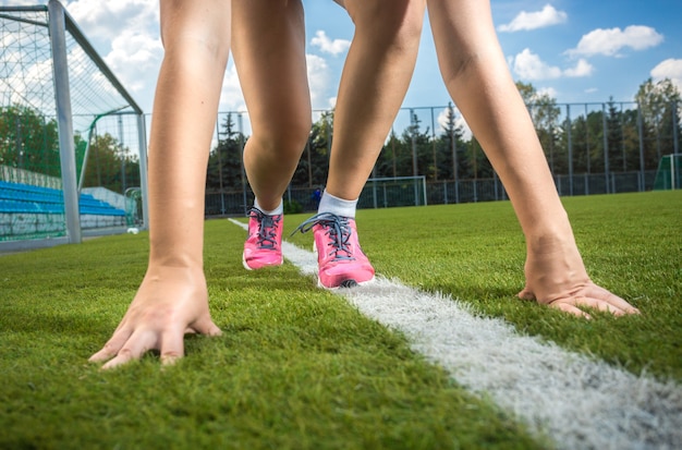 Foto primo piano di una donna sportiva esile che si prepara a correre su una pista in erba