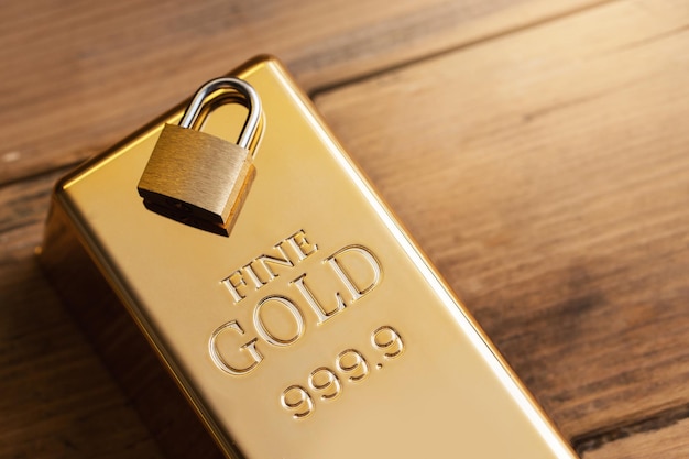 Closeup shot of a small brass padlock on a large shiny gold bar Concept of bank investment safety