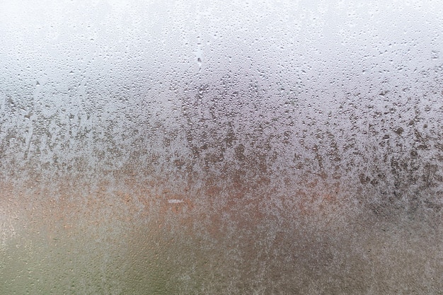 무미건조한 날에 물 방울이 있는 김이 나는 창문의 클로즈업 샷.