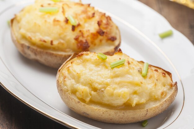 Closeup shot of stuffed baked potatoes with cheese and egg on a white plate