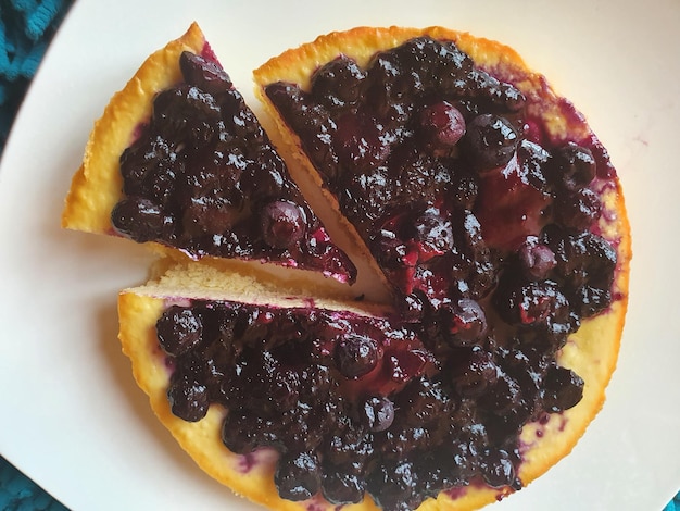 A closeup shot of tasty Blueberry pie with one sliced piece on a white plate