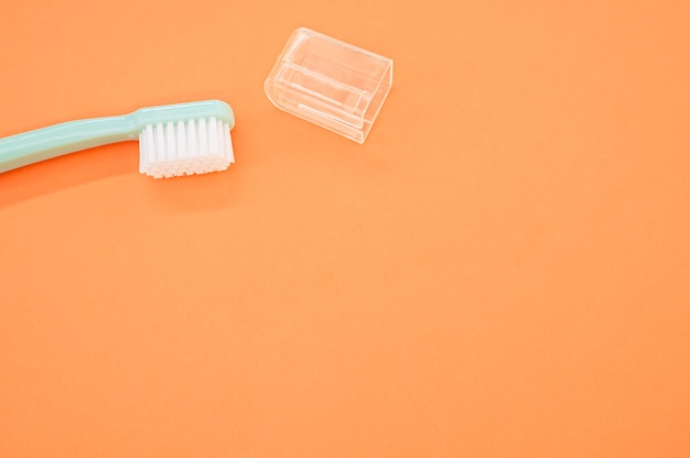 Closeup shot of a toothbrush with a plastic cap isolated on an orange background