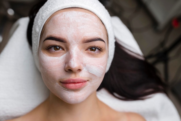 Primo piano di una donna che riceve un trattamento facciale con maschera di argilla cosmetologia e spa