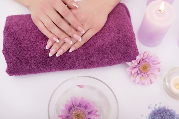 Colpo del primo piano di una donna in un salone del chiodo che riceve una manicure da un'estetista con cotone idrofilo con acetone. donna che ottiene manicure per unghie. lima per unghie da estetista a un cliente