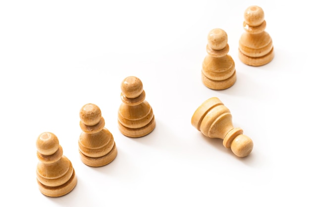 Closeup shot of wooden chessmen standing with one chess pawn lying Concept of social issue and bullying