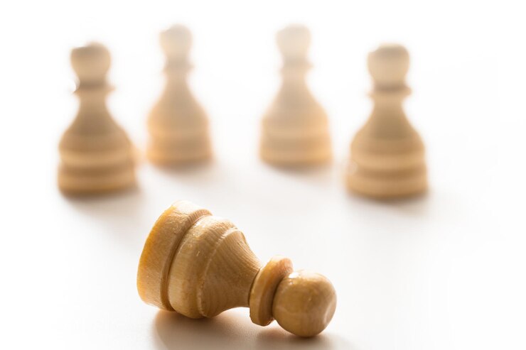 Photo closeup shot of wooden chessmen standing with one chess pawn lying concept of social issue and bullying