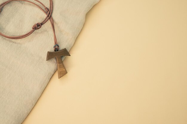 Closeup shot of a wooden tau cross necklace on a wooden background