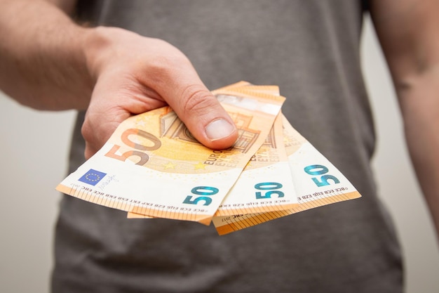 closeup shot of a young man holding 150 euros in his hand