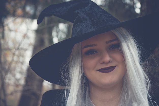 Closeup shot of a young smiling Caucasian girl wearing a witch costume and makeup for Halloween