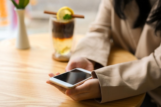 Closeup shot A young woman in casual suit sitting in the coffee shop and using her smartphone