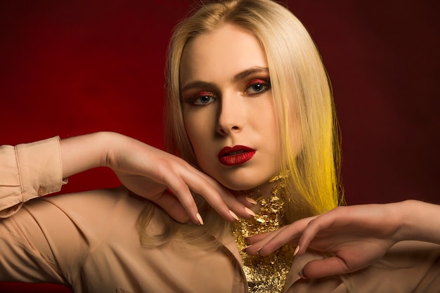 Photo closeup shot of young woman with bright makeup and golden foil. red and yellow studio light