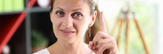 Closeup of shrewd smart woman in casual clothes female shows gesture with her index finger up