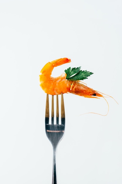 Photo closeup of a shrimp chopped on a fork on a white background