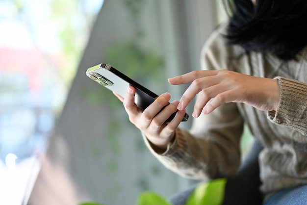 Вид сбоку крупным планом Женщина, использующая свой смартфон, касаясь экрана мобильного телефона