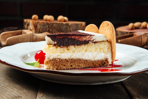 Closeup side view on tiramisu cake with berry sauce on the wooden table