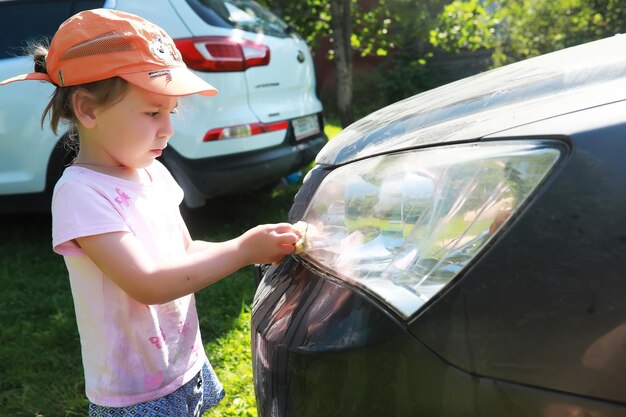 Closeup side view of a young boy washing car with sponge