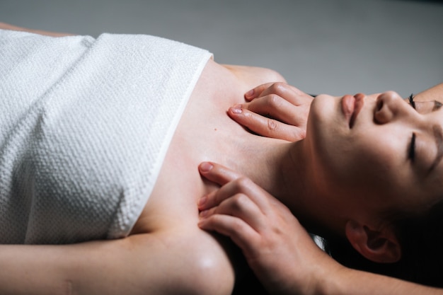 Closeup side view of young woman lying down on massage table during shoulder and neck massage