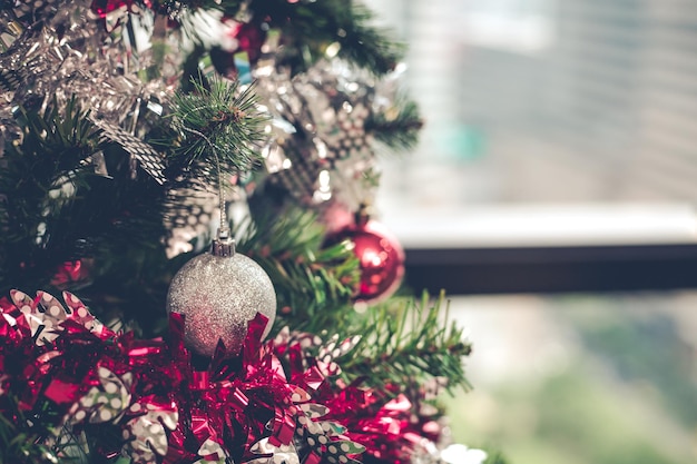 Closeup of silver ball hanging from a decorated Christmas tree with copy space. Christmas and New year holidays background.