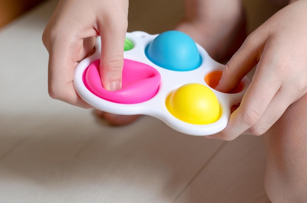 Closeup of a simple dimple in the hands of a child A child plays with a modern toy simple dimple