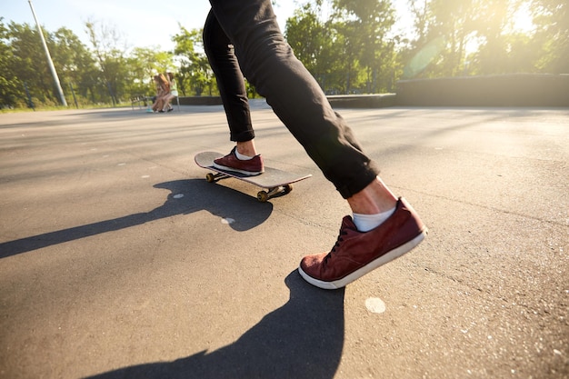 Primo piano dei piedi degli skateboarder durante il pattinaggio in skate park uomo che cavalca su skateboard vista isolata dal basso angolo di tiro