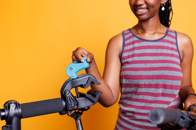 Closeup of skilled black woman inspecting and adjusting repairstand ensuring safe support for bicycle maintenance detailed view of african american female preparing to clamp bike frame for fixing