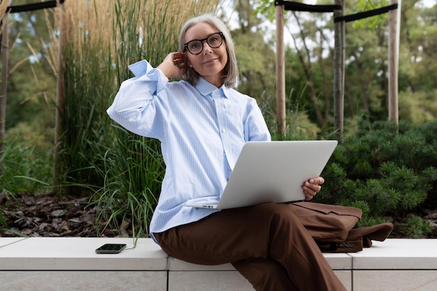 Closeup of a slender wellgroomed pretty grayhaired business woman pensioner against the background