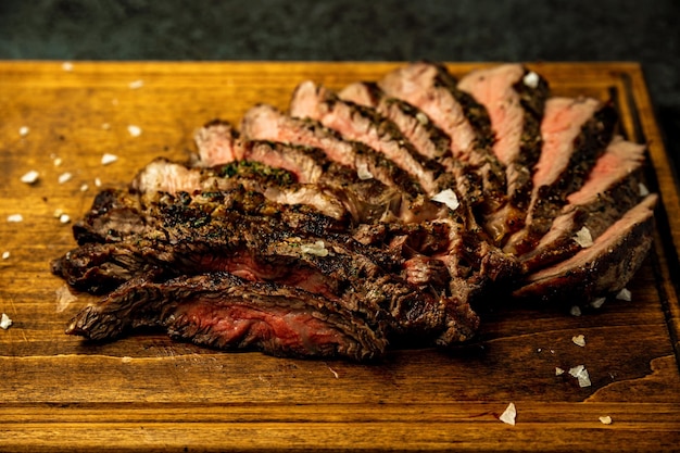 Photo closeup of sliced boneless ribeye steak served on a wooden board in a restaurant