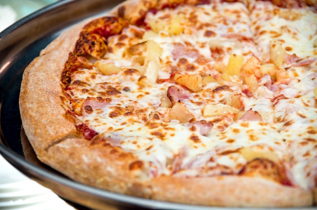 Photo closeup of a sliced pizza with pineapple