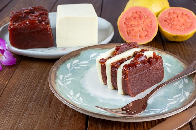 Closeup of slices of guava sweet and curd cheese next to a copper knife and fork