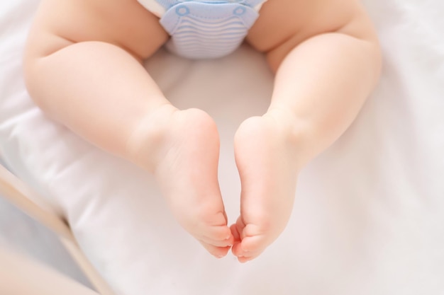 Closeup of a small child lying in a crib on white bed linen legs of a healthy child