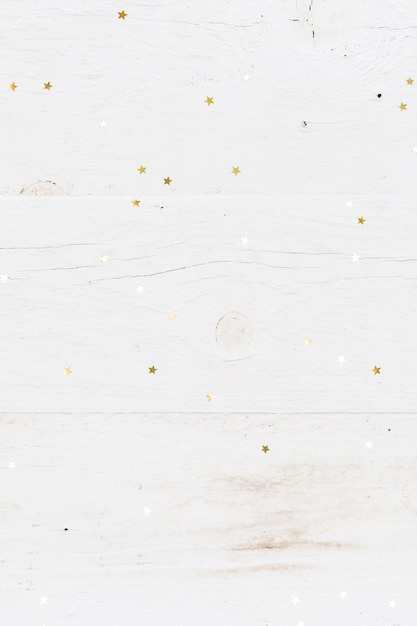 Closeup of small golden stars confetti on vintage white wooden background