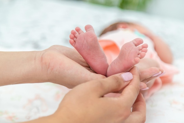 女性または母親の手の中の生まれたばかりの赤ちゃんの小さな足のクローズアップ子供との瞬間