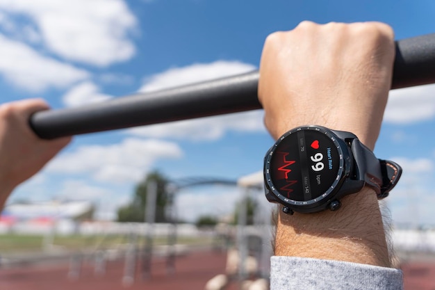 Photo closeup of smart watch health tracker with heart rate shown on the screen modern stylish and innovation wearable device athlete checks his heart rate before training at the stadium heart beat