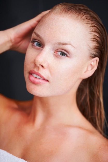 Closeup of a smiling female wrapped in a towel against white Closeup of a cute wrapped in a bath towel against black background