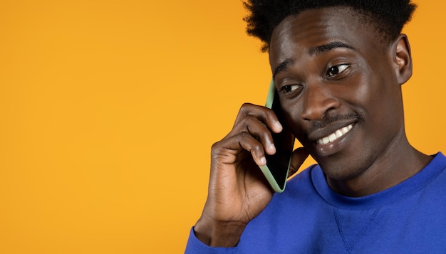 Closeup of smiling happy young black man talking on phone