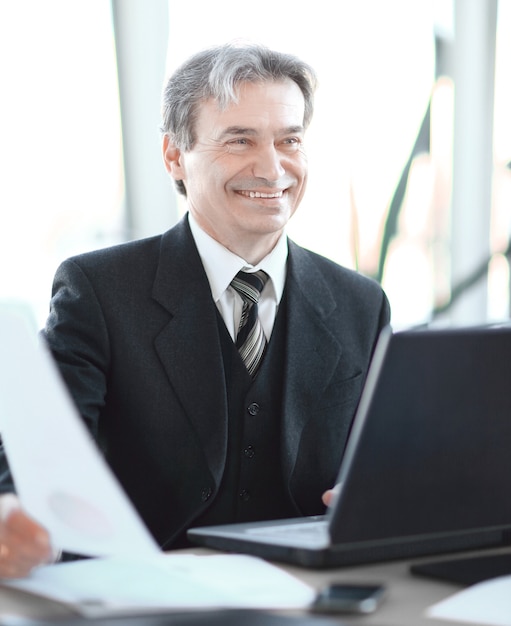 Closeup. smiling senior businessman sitting at his Desk