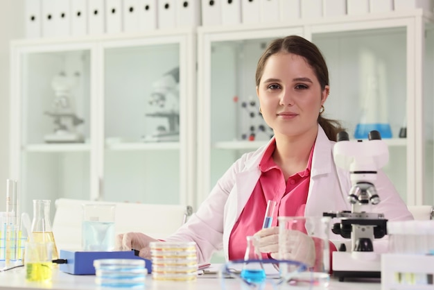 Primo piano dello scienziato sorridente della donna che posa nell'assistente di laboratorio del laboratorio di ricerca che si siede a